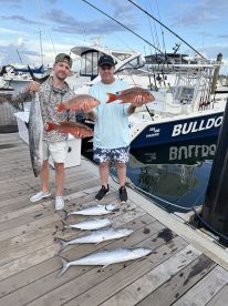 Two anglers proudly displaying their catch of Snapper and Kingfish on the dock, with the 'BULLDOG' charter boat in the background.
