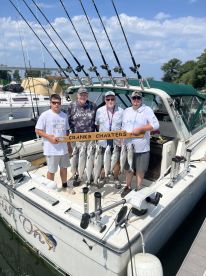 A group of anglers proudly displaying their catch of several trout on a charter boat, showcasing a successful day on the water.