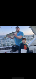 A proud angler holding a large Walleye while fishing with a child on a boat, showcasing a successful day on the water.