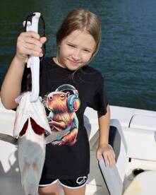 A young angler proudly displaying a freshly caught fish while on a boat, showcasing a fun day of fishing.