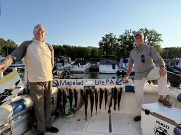 Two anglers proudly displaying their catch of Walleye on a catch board aboard a fishing boat in Erie, PA.
