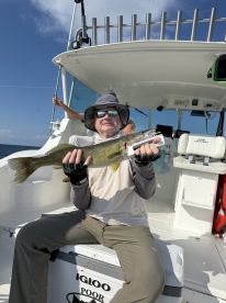 An angler proudly displaying a Walleye on a fishing boat, showcasing a successful catch during a sunny day on the water.