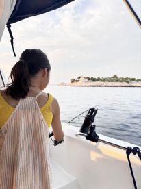 A young angler casting off the side of a boat while fishing near a scenic island, showcasing a tranquil fishing environment.