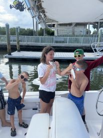 A group of young anglers proudly displaying their catch of fish on a boat, enjoying a fun family fishing trip.