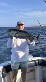 Young angler proudly displaying a Yellowfin Tuna while fishing offshore, showcasing a vibrant ocean backdrop.