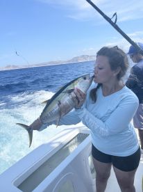 Angler kissing a large Yellowfin Tuna while fishing on a sportfishing boat in open waters.