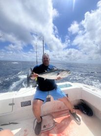 Angler proudly displaying a large fish while fishing on a boat in open waters, showcasing a successful day at sea.