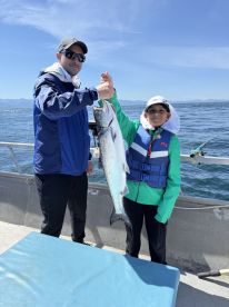 A proud moment for a young angler and an adult, showcasing a large Salmon caught during a fishing trip on the open water.