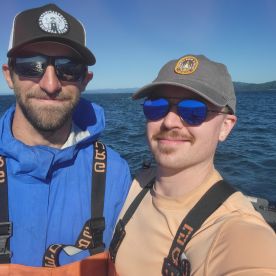 Two anglers posing for a selfie on a boat, enjoying a day on the water.