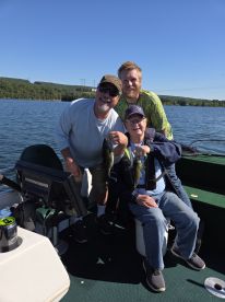 Three anglers proudly displaying their catch of Largemouth Bass while enjoying a sunny day on the water.