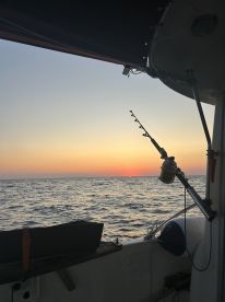 A serene view from inside the boat at sunset, showcasing fishing gear and the calm ocean waters.