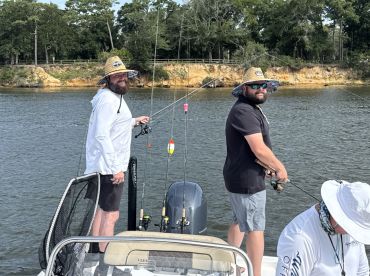 Two anglers actively fishing from a boat in a scenic freshwater environment, showcasing a relaxed fishing experience.