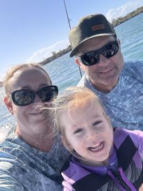 A family enjoying a day on the water, with a child smiling in a life jacket, capturing a joyful moment on the boat.