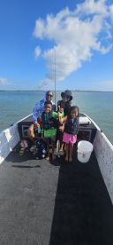 A family enjoying a fishing trip on a boat, with children proudly displaying their catch in a scenic waterway.