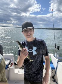 A young angler proudly displaying a caught fish while aboard a fishing boat, enjoying a day on the water.