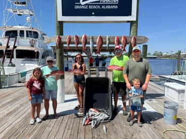 A family proudly displaying their catch of Red Snapper at Zeke's Marina in Orange Beach, Alabama, after a successful fishing trip.
