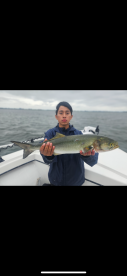A young angler proudly displaying a large fish while on a boat, showcasing a successful fishing trip.