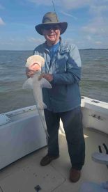 An angler proudly displaying a caught shark while on a fishing trip, showcasing the excitement of the catch.