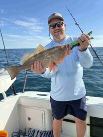 Angler proudly displaying a large Grouper while fishing offshore, showcasing a successful day on the water.