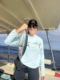 An angler proudly displaying a large fish aboard a boat, showcasing a successful fishing trip in open waters.