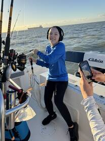 A young angler joyfully reeling in a fish aboard a Cobia boat, showcasing the excitement of fishing on the open water.