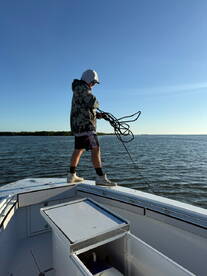 A young angler preparing to cast off from the bow of a boat, showcasing the excitement of fishing in a serene waterway.