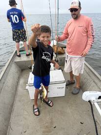 A young angler proudly displaying a caught fish while fishing from a small boat, enjoying a day on the water.