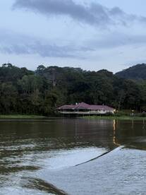 Scenic view of a fishing lodge along the river, surrounded by lush greenery, showcasing a tranquil fishing environment.