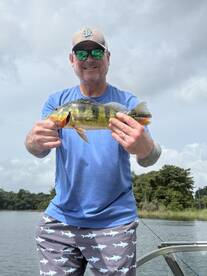 An angler proudly displaying a vibrant Yellow Perch while fishing on a serene lake, showcasing a relaxed fishing environment.