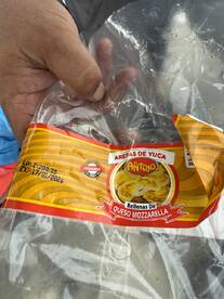 An unclear image showing a hand holding a package of yuca arepas with mozzarella cheese, likely taken during a fishing trip.