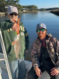 Two anglers proudly displaying a freshly caught Redfish while enjoying a day on the water.