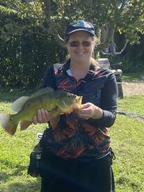 An angler proudly displaying a vibrant Peacock Bass in a lush outdoor setting, showcasing a successful fishing trip.