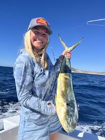 A young angler proudly holding a vibrant Mahi Mahi while fishing in open waters, showcasing a successful catch.