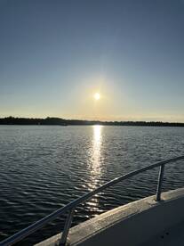 A serene sunset view over calm waters, captured from the side of a boat, highlighting the tranquil fishing environment.