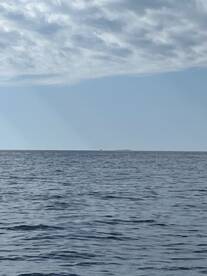 A distant view of the ocean with a cloudy sky, lacking any clear subject or fishing activity.