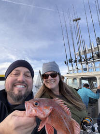 Two anglers proudly displaying a vibrant Rockfish while enjoying a fishing trip on a charter boat.