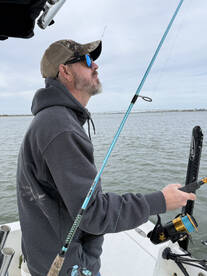 An angler casting a line while fishing on a calm day, showcasing the excitement of the sport.