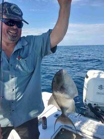 Angler proudly displaying a freshly caught fish while fishing on a boat in open waters.