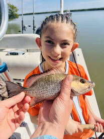 A young angler proudly displaying a freshly caught fish while enjoying a day on the water.