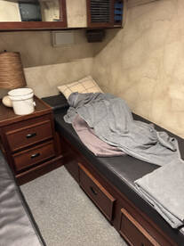 Cozy cabin interior featuring a comfortable seating area with blankets and storage drawers, ideal for relaxation during fishing trips.