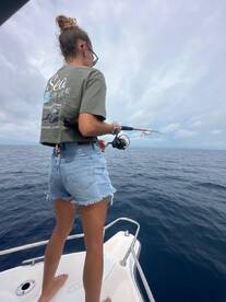 A young angler casting a line from the bow of a boat in open water, showcasing the excitement of deep-sea fishing.
