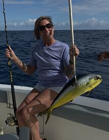 Angler proudly displaying a vibrant Mahi Mahi while fishing offshore, showcasing a beautiful day on the water.