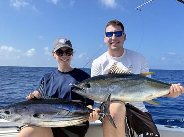 Two anglers proudly displaying their catch of Yellowfin Tuna while out on a deep-sea fishing trip.