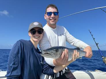 Two anglers proudly displaying a large fish while enjoying a sunny day on the water.