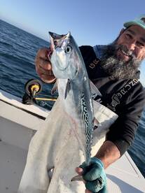 Angler proudly displaying a freshly caught fish while on a fishing trip, showcasing the vibrant colors of the fish against the backdrop of the ocean.
