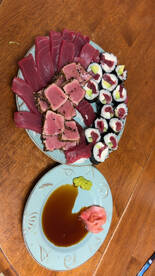 A beautifully arranged plate of sushi and sashimi, featuring various cuts of tuna, wasabi, and soy sauce, perfect for a seafood feast.