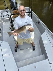 Angler proudly displaying a large striped bass aboard a fishing boat, showcasing a successful day on the water.