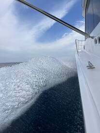 A dynamic view of the boat slicing through the water, showcasing the wake and the expansive sky above.