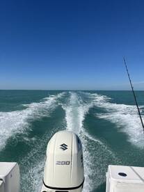 A scenic view from the back of a boat, showcasing the wake and clear blue skies while heading out for a fishing adventure.