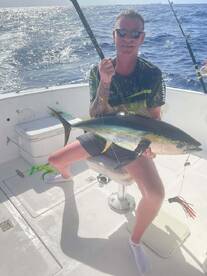 Angler proudly displaying a large Yellowfin Tuna while fishing offshore, showcasing a successful day on the water.